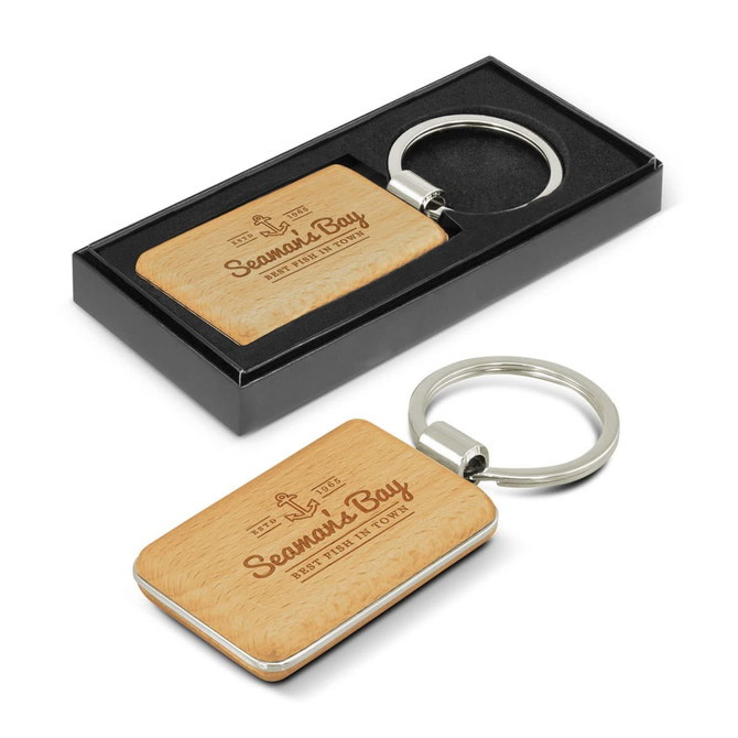 A rectangular key ring with a wooden surface and a metal keychain, presented in a black box.