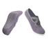 A pair of grey yoga socks featuring a non-slip dotted sole and a crisscross strap design.