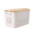 A dual-compartment lunch box in white with a bamboo lid, featuring a secure latch and branding.