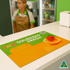 A vibrant orange counter mat featuring fruit graphics and a logo, set on a retail counter.