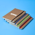 A stack of five Jodha Notebooks with kraft covers and coloured elastic bands in blue, green, and red. Each has a logo.