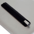 A metal pen in a black holder, placed on a grey surface, featuring a silver clip and end.