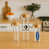 A drink bottle collection featuring three clear glass bottles with wooden lids and handles.