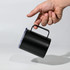 A drink mug in matte black with a handle, being held, featuring a transparent lid.