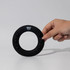 A hand holding a black silicon wrist disc with buttons and a logo at the top.
