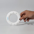 A hand holding a white silicone wrist disc featuring five raised buttons and a logo.