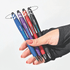 A hand holds four Spinner Fidget Pens in blue, purple, red, and black, each with a stylus tip and unique design.