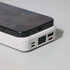 A white power bank with a digital display, featuring multiple ports, placed beside a smartphone.
