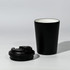 A black travel cup with a removable lid, featuring a sleek design and a contrasting inner colour.