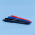 Four pens arranged on a blue surface: one red, two shades of blue, and one black, each with a logo.