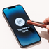 A red metal pen is held above a smartphone displaying a 'Tap Here to Open' screen. The phone has a logo on it.