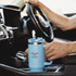 A drink bottle in light blue, featuring a handle and a straw, positioned in a car's centre console.