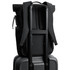 A black rolltop backpack is secured on a black suitcase, featuring padded straps and a side pocket.