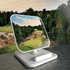 A wireless charger with a white stand, featuring a scenic landscape image on its surface.