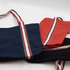 A navy, red, and black canvas tote bag with striped handles, featuring a logo on one side.