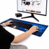 A desk mat featuring a blue city skyline design, with a keyboard and hands positioned on it, next to a monitor.