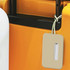 A luggage tag in a soft beige colour attached to the handle of an orange suitcase. It has a logo on the tag.