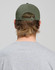 A cotton twill unstructured cap in olive green, viewed from the back, worn by a person with medium-length hair.