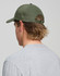A green cotton twill unstructured cap viewed from the back on a person with long hair, wearing a grey shirt.