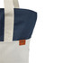 A tote bag featuring a navy blue top and a cream bottom, with a small logo tag.