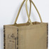 A jute tote bag in natural brown, featuring decorative elements and sturdy handles. Brand logo is present.