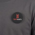 A round black magnetic badge featuring a logo and placed on a grey shirt.
