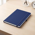A navy A5 journal with a textured cover, elastic band closure, and white pages, resting on a wooden desk.