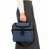 A blue cooler bag is being held by a person wearing a light sweater and grey pants. The bag features a logo.