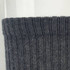 A pair of grey socks with a ribbed cuff, featuring a branding logo.