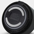 A wireless charging speaker with a round base, featuring a smooth black surface and a vented design. It has a branding logo.