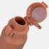 A drink bottle in a soft terracotta colour, featuring a flip-top lid and a metal loop for attachment.