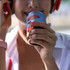 A drink bottle held by a person wearing headphones, featuring a blue design and a logo.