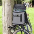 A grey 20 Can Backpack Cooler with water bottles inside, resting on a bicycle by a tree in a grassy area.