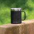 A black stainless steel coffee mug with a silver rim and handle, featuring a logo.