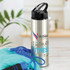 A drink bottle with a stainless steel finish, black flip cap, and a logo featuring fitness-themed graphics.