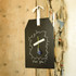 A blackboard tag with a decorative border, featuring a white ribbon and a simple flower arrangement.
