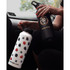 A drink bottle with a white body featuring a fruit design, alongside a black bottle with a logo. Both are in a vehicle.
