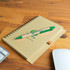 A notebook with a spiral binding and a green Matador pen resting on it, featuring a printed logo.