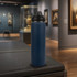 A drink bottle with a sleek navy blue finish and a black lid, positioned on a surface in an art gallery setting.