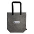 A gray tote bag with black handles featuring a printed logo label that reads "NOMADSCAPE."