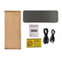 A black speaker with a mesh cover, accompanied by charging cables, a manual, and packaging.