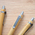 A set of bamboo pens with metallic tips and clips, arranged on a wooden surface.