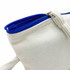 A cosmetic bag in cream with a blue zip, featuring a textured fabric and a handy side loop.