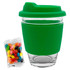 A glass coffee cup with a green silicone lid and sleeve, accompanied by a pack of colourful jelly beans.