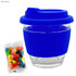A glass coffee cup with a royal blue silicone lid and band, paired with a pack of colourful jelly beans.