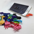 A collection of colourful mobile key stands in various shapes, with a phone displaying a website propped up.