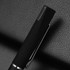 A sleek black metal pen with a silver clip, resting on a textured black surface. The pen features a logo.