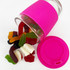 A reusable glass coffee cup with a pink silicone sleeve, filled with assorted jelly lollies spilling out.