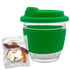 A green glass coffee cup with a silicone lid and sleeve, accompanied by a packet of mixed lollies in various colours.