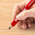 A red carpenter pencil held in a hand, marking a line on a wooden surface.
